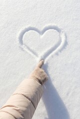 Hand drawing heart in snow close up winter love concept background with copy space
