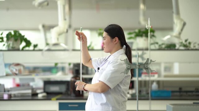 Female researcher in laboratory holding a test tube and carefully observing its contents