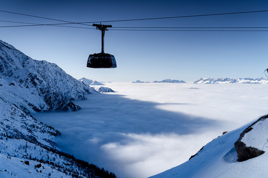 Cable car on backdrop of high mountains is running to summit of the Aiguille du Midi in winter, Chamonix-Mont-Blanc, French Alps.