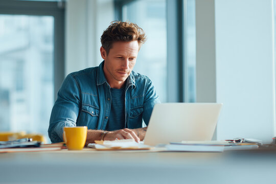 businessman in casual dress working on laptop, natural light from big window