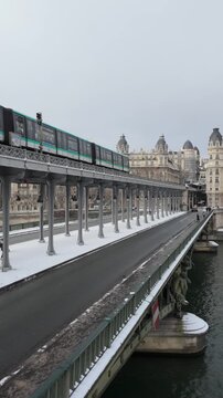 Metro on Bir Hakeim bridge in winter with snow