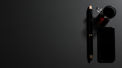 Minimal dark workspace flat lay with pencil, smartphone, and coffee cup on black background with copy space