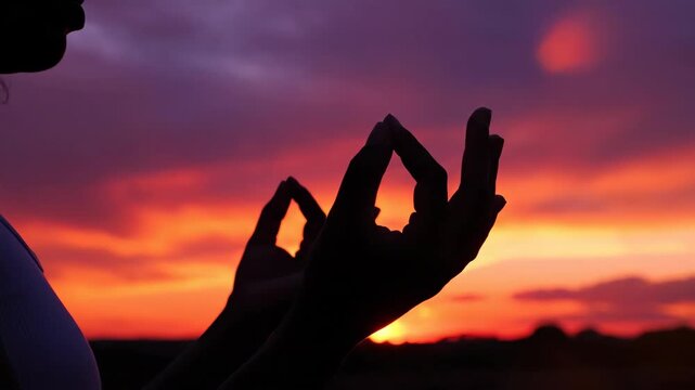 Woman practicing gesture at sunset. Spiritual mudra hand pose for meditation and mindfulness in nature. Concept of peace and calm.