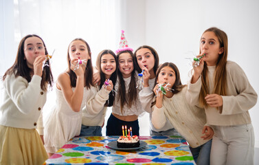 Festive group of preteen pupils aving fun in birthday posing with cake