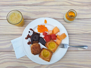 Breakfast: pastries, fruits, orange juice on the table. Top view