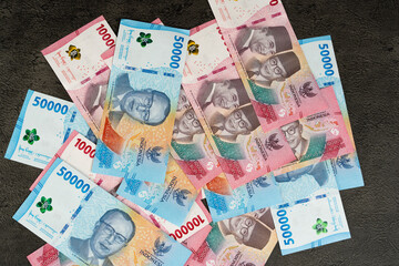 Indonesian rupiah banknotes of 100000 and 50000 on dark textured background with copy space, money and finance concept for business, economy, savings, and investment