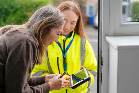Two people work together on a task outside a house in a residential area on a cloudy day