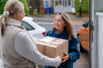 Package delivery takes place at a front door between two people in a residential area