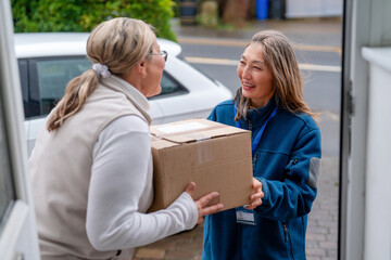 Delivery person hands package to customer at home on a sunny day in the afternoon