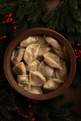 Traditional Ukrainian dumplings known as varenyky served in a rustic bowl, surrounded by fir branches and red berries.