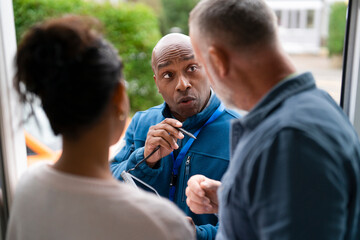 Fototapeta premium Man speaks to couple at their door in a residential area during daytime