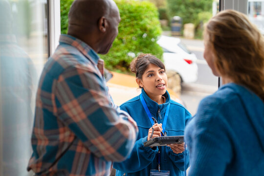 Community service worker interacts with two residents outside a building during the day