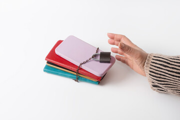 A hand reaches for a stack of cell phones, chained and locked. Information overload, digital fatigue, digital detox