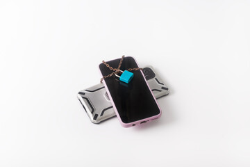 Two smartphones, tied with a chain and padlocked, on a white background. Digital overload and fatigue. Gadget addiction