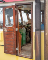 Interior view of the wheelhouse showing controls on a fishing boat docked at a marina during a cloudy day © Ulrich