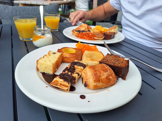 Breakfast: pastries, fruits, orange juice on the table. The man is having breakfast
