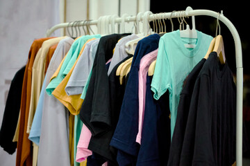 colorful blank tshirts neatly displayed hanging on a white clothing rack.