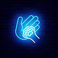 Dog or cat paw in human hand neon icon. Animal care center. Veterinary, training and grooming. Domestic animal footprint. Friend pet. Light sign. Editing text. Vector stock illustration