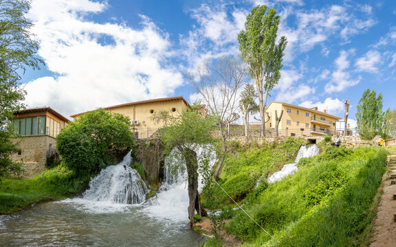 Trillo, Spain, Italy - May 05, 2025: Waterfalls running through the town of Trillo in Guadalajara, with tourists strolling around the area in Trillo, Spain.