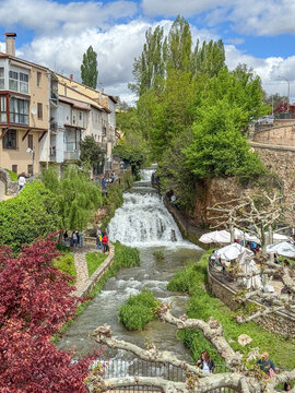 Trillo, Spain, Italy - May 05, 2025: Waterfalls running through the town of Trillo in Guadalajara, with tourists strolling around the area in Trillo, Spain.