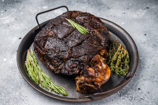 Slow cooked venison roast leg. Braised game meat of deer with bone. grey background. top view
