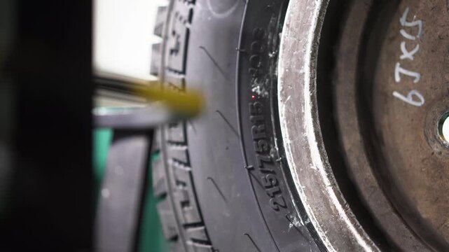Close-up shot of tire tread wear inspection using a measuring tool