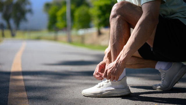 Closeup runner man tying lace running shoes in the park