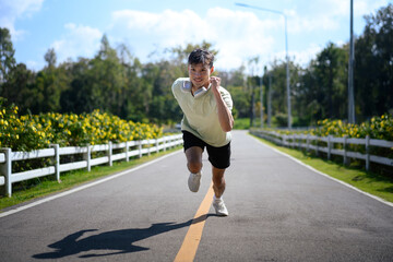 Man running at full speed on an open road, expressing energy, effort, and strong commitment after the moment of starting. © Prathankarnpap