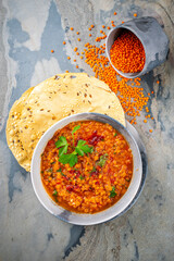 Indian dal fry red lentils with chili papadam servied as top view in iron pot