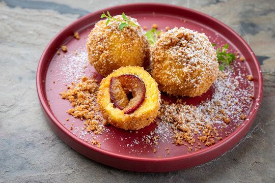 Traditional Austrian zwetschgenkn&ouml;del - plum dumpling stuffed with prune in a dough coat served as close-up with cinnamon butter crumbles
