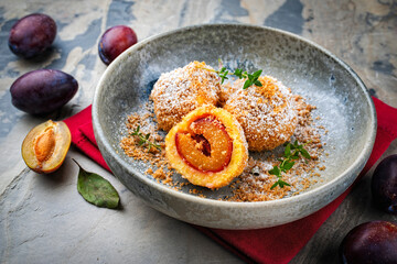 Traditional Austrian zwetschgenkn&ouml;del - plum  dumpling stuffed with prune in a dough coat served with cinnamon butter crumbles
