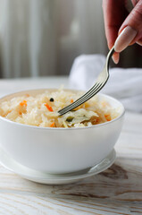 Sauerkraut in a white bowl on a rustic wooden table
