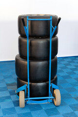Racing tires stacked on blue transport hand cart