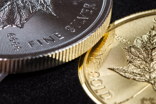 Close-up of the inscription &ldquo;fine silver&rdquo; on a silver coin lying on a gold coin labeled &ldquo;fine gold,&rdquo; representing precious metal prices and the gold-to-silver ratio.