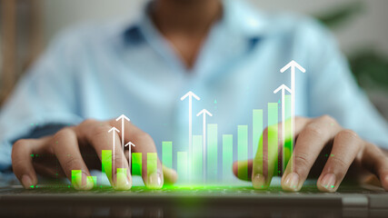 Businessman hands typing on laptop with growing green bar graph and arrows icons.
