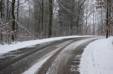 Obraz premium Mit Schnee bedeckte Straßen Kurve in einem Waldgebiet. Unfall Gefahr bei Rutschige Fahrbahn im Winter.