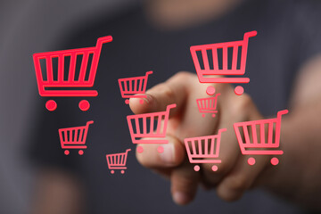 Hand pointing at floating shopping cart icons symbolizing online shopping, e-commerce, and digital...