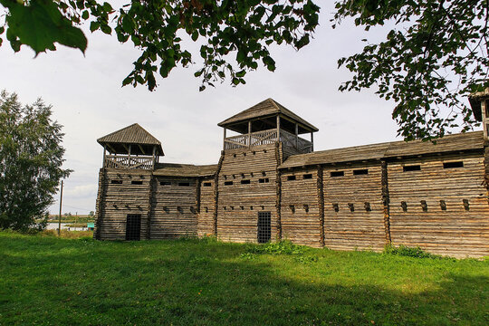 Historic wooden fortress with log walls and watchtowers, standing in a green landscape, representing medieval defense architecture and cultural heritage.