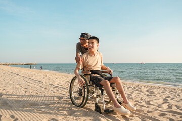 A young man with disability enjoying beach time with caregiver in wheelchair. Natural family moment, inclusion, accessibility, and positive disabilities lifestyle outdoors.