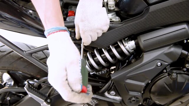 The process of replacing or servicing the air filter on a motorcycle. A mechanic removes plastic from a motorcycle. Removing plastic parts from a motorcycle.