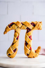 Delicious baked lattice pie dough forming the Greek mathematical symbol pi filled with a sweet berry filling on a marble surface