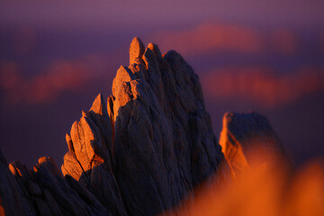 Dramatic mountain peak illuminated by warm light at sunset with purple and orange hues in the sky and clouds  landscape photography