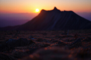 Magnificent mountain peak silhouette against a vibrant orange and purple sunset sky creating a breathtaking natural landscape scene