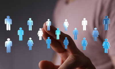 Hand reaching towards a collection of virtual people icons, representing social networking, technology, and com