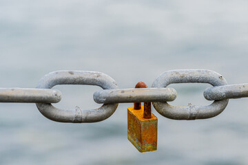 Rusted padlock hanging on a chain