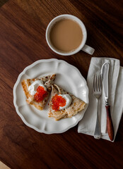 Crepes with greek yogurt and red caviar and coffee on a wooden background, top view