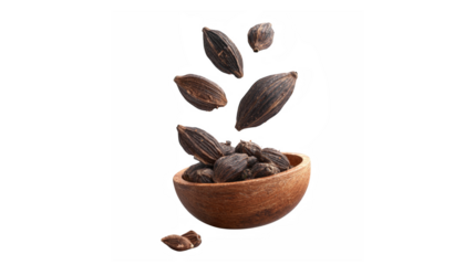 Black cardamom pods falling from a wooden bowl