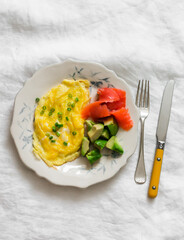 Delicious breakfast, brunch - omelette, avocado, lightly salted salmon on a light background, top view
