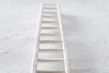 simple white ladder positioned on a soft gray surface, showcasing a minimalist design