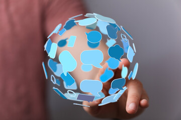 Close-up of a hand holding a globe of communication icons, conveying connectivity and global network concept.